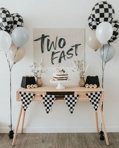 a table topped with balloons and cake next to a sign that says, two fast