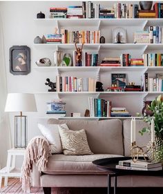 a living room filled with furniture and lots of books on the shelves above it is a coffee table