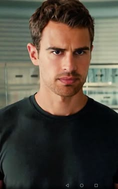 a man in a black t - shirt looking at the camera with an intense look on his face