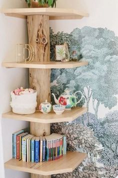 three wooden shelves with books and plants on them in a corner next to a wall mural