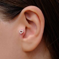 a woman's ear is shown with a heart shaped diamond stud in the middle