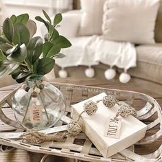 a glass vase filled with flowers sitting on top of a tray next to a couch