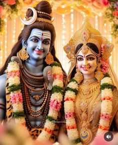 two people dressed up as hindu deities in front of a decorated stage with flowers and garlands