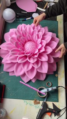 a large pink flower sitting on top of a table next to scissors and pliers