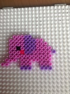 an elephant made out of legos sitting on top of a white surface with pink and purple beads