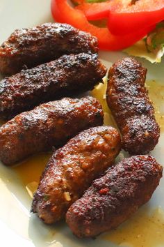 several sausages are on a plate with tomatoes and lettuce