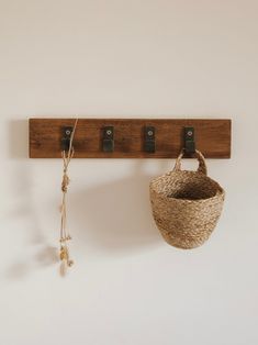 a basket hanging on a wall next to two hooks and a keychain attached to it