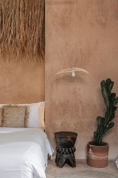 a bed in a room with a plant next to it and a wall hanging over the headboard