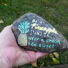 a hand holding a rock that says be a pineapple stand tall wear a crown be sweet