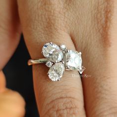 a woman's hand holding an engagement ring with three stones