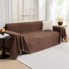 a living room with a couch covered in a brown blanket and two lamps on the side tables