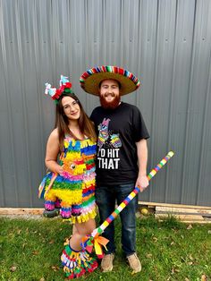 a man and woman dressed up in mexican garb posing for a photo with sticks