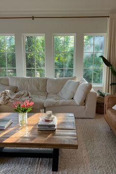 a living room with couches, coffee table and large windows in the back ground