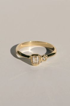 a yellow gold ring with two baguettes on the side and a diamond in the middle