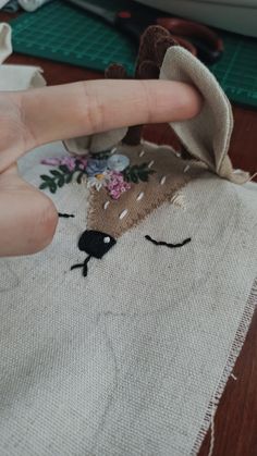 a hand is pointing at a piece of fabric with a deer on it and flowers