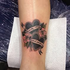 a tattoo on the leg of a woman with a heart and ribbon around her neck