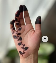 a woman's hand with black leaves painted on it