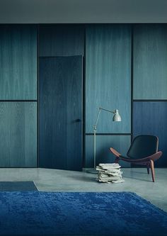 a blue rug and chair in a room with wooden paneling on the walls,