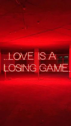 a large neon sign that says love is a losing game in the middle of an empty room