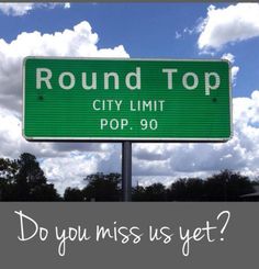 a green road sign that says round top city limit pop 90 do you miss us yet?