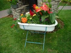 a bathtub filled with lots of flowers sitting in the grass