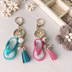 three pairs of crocheted shoes with tassels and pearls hanging from them