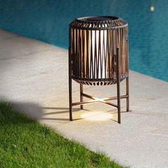 an outdoor fire pit next to a swimming pool with grass on the ground and blue water in the background