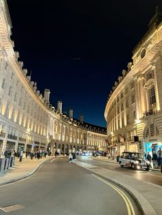 an empty city street at night with people walking and cars driving on the side walk