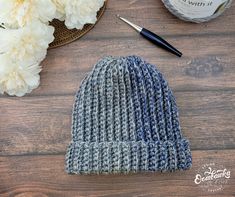 a knitted hat sitting on top of a wooden table next to a cup of coffee