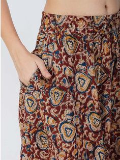 Our Venessa printed skirt, made from soft cotton fabric, features an A-line silhouette perfect for most body types. This regular-fit Kalamkari skirt with an elasticated waistband is a great option for all-day wear, especially during the summer months. Kalamkari is a highly popular form of block-printed cotton textile produced with the help of kalam, meaning pen. During the process, a sharp-pointed pierced bamboo regulates the flow of color/organic dye on the fabric. This maroon-colored skirt comes with one pocket, making it an ideal casual-wear wardrobe staple. To add some extra fun, you can pair it with a monotone shirt or top and elevate your style effortlessly. Material: Cotton Style/Print: Kalamkari Waist: 30” Length: 39” Fit: A-line Occasion: Casual Color: Maroon Lining: No Cotton Long Skirt With Floral Print, Relaxed Fit Brown Cotton Skirt, Casual Printed Cotton Skirt, Multicolor Cotton Knee-length Skirt, Multicolor Knee-length Cotton Skirt, Casual Cotton Patterned Skirt, Cotton Floral Print Knee-length Skirt, Knee-length Cotton Skirt With Floral Print, Brown Cotton Gathered Skirt Bottoms