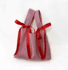 a red and white gingham bag with a bow on the front, sitting on a white surface