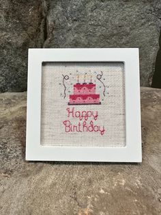 a cross stitch birthday cake with candles on it is displayed in a white framed frame