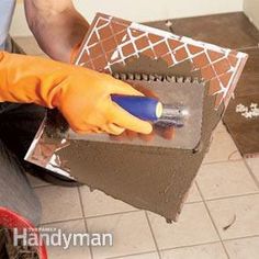 a person in orange gloves and yellow rubber gloves is painting a wall with brown tiles