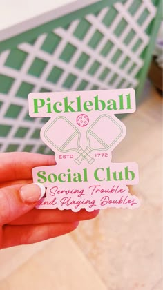 a person holding up a sticker that says pickleball social club