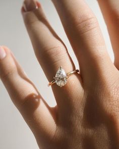 a woman's hand with a diamond ring on top of her finger, showing the center stone