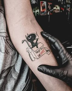 a person with a tattoo on their arm holding a black glove and some scissors in front of them