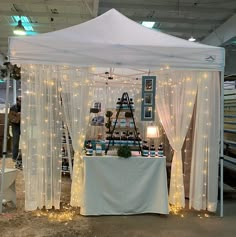 a tent set up with white curtains and lights