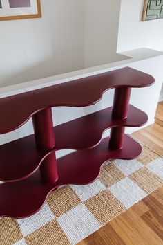 a red shelf sitting on top of a hard wood floor next to a white wall