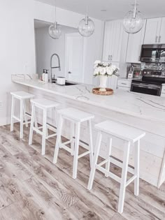 a kitchen with white counter tops and stools