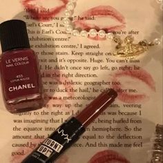 an open book with lipstick on it next to a bottle of chanel nail polish