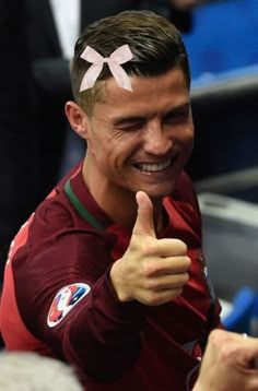 a man giving the thumbs up sign in front of other people at a soccer game