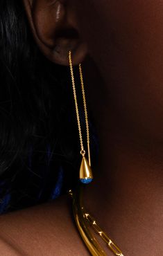 a close up of a woman's neck wearing a gold necklace and earring