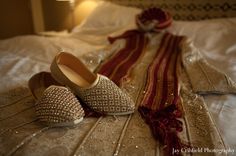 two pairs of shoes sitting on top of a bed next to a red and white scarf