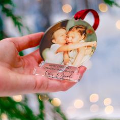 a hand holding a christmas ornament with a photo of two children on it