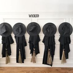 five hats are hanging on the wall with tassels in front of them and labeled wicked