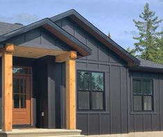 a gray house with wooden pillars and windows