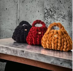 three purses sitting on top of a table next to each other in different colors