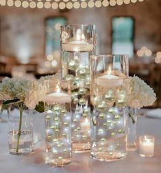 the centerpieces are filled with white flowers and lit candles in glass vases