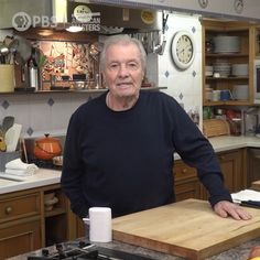 an older man standing in a kitchen next to a cutting board