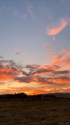 the sun is setting over an open field